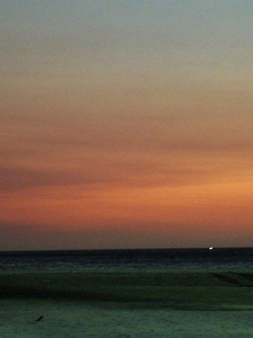 Drei junge Männer stehen bei Sonnenuntergang an der kolumbianischen Karibikküste