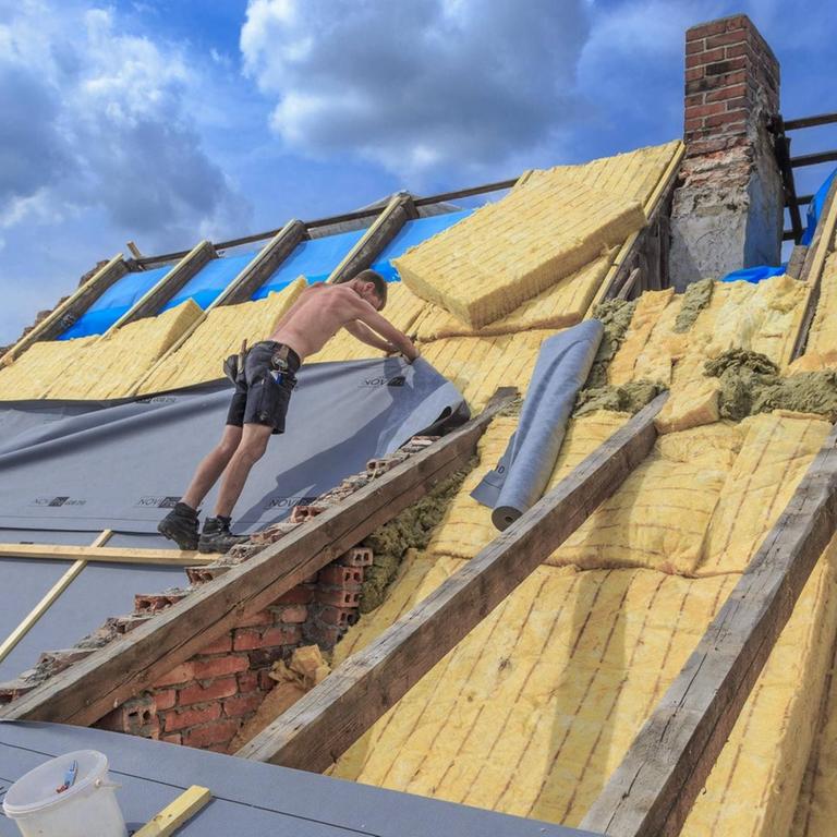 Dachdecker dämmen das Dach eines Hauses in Cottbus mit Glaswolle