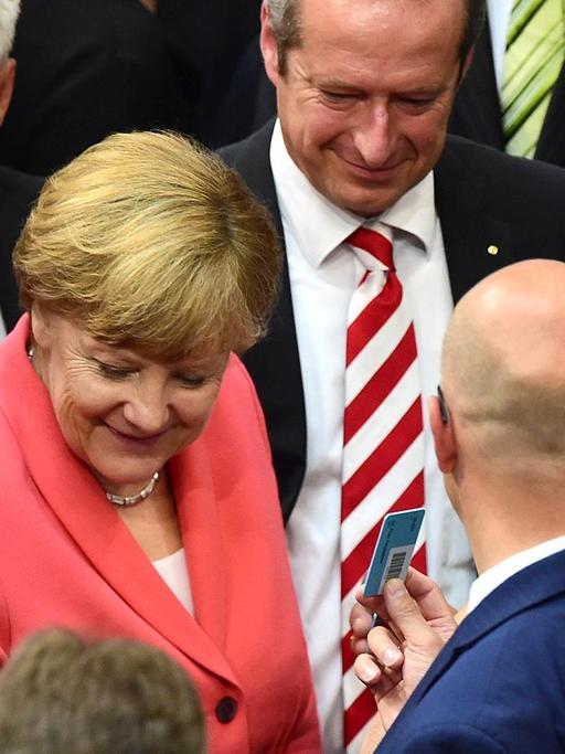 Bundeskanzlerin Angela Merkel (CDU) legt während der Abstimmung zu Verhandlungen über ein neues Griechenland-Hilfspaket ihren Stimmzettel in die Urne. Sie wird dabei von weiteren Bundestagsabgeordneten umringt, darunter Vizekanzler Sigmar Gabriel (SPD).
