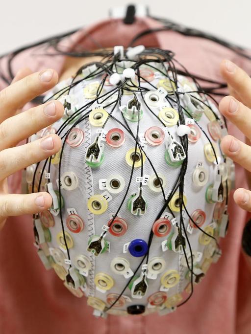 Ein Mann trägt eine EEG-Kappe