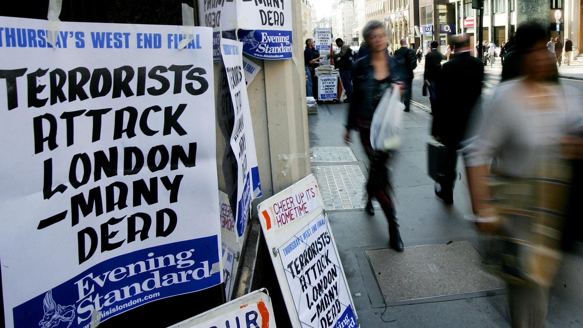 Fußgänger laufen am 07.07.2005 an einem Zeitungsstand vorbei, an dem die Terroranschläge auf die U-Bahn in London angekündigt werden.