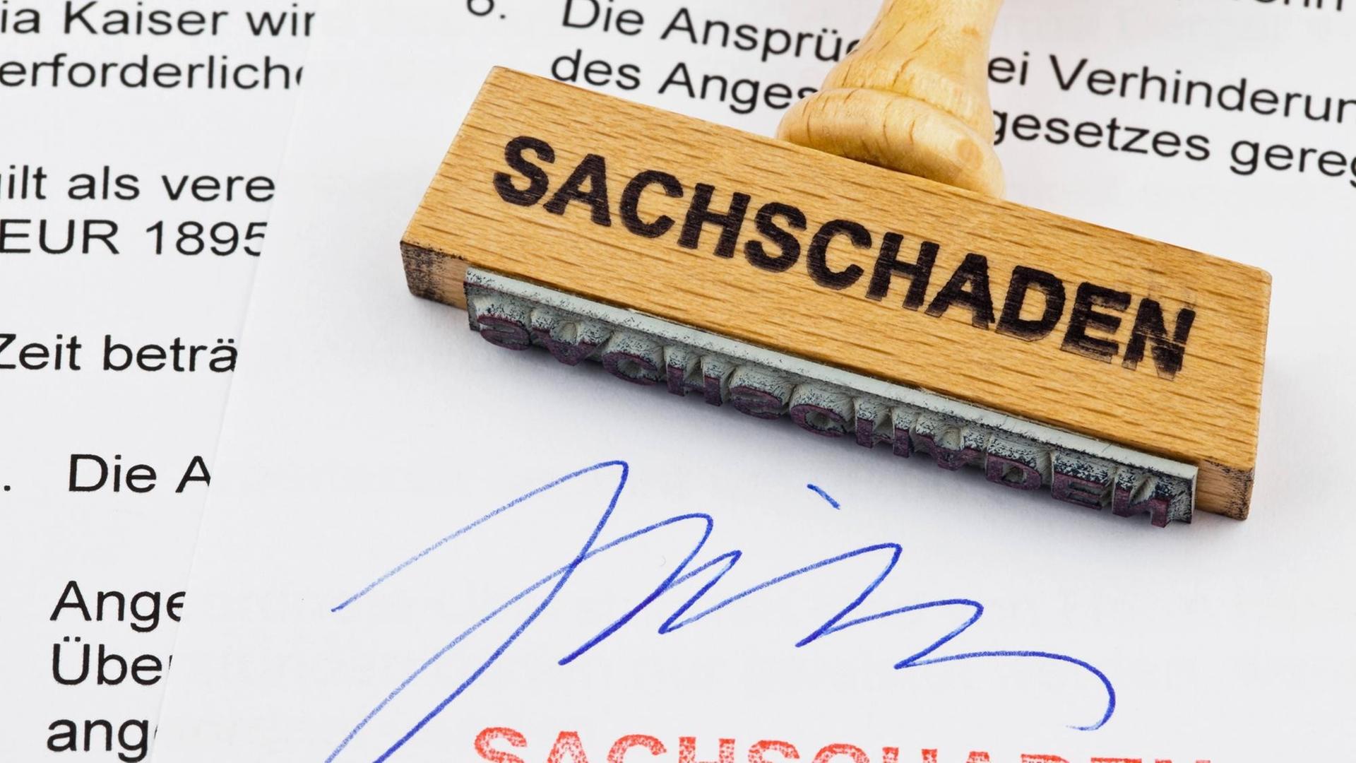 Ein Stempel aus Holz liegt auf einem Dokument. Deutsche Aufschrift: Sachschaden