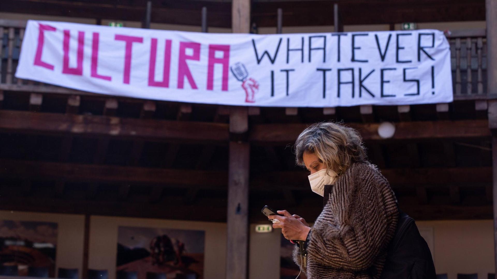 Eine Mitarbeiterin des pandemiebedingt geschlossenen Globe-Theaters in Rom steht vor einem Plakat mit dem Schriftzug: "Cultura - Whatever it takes".