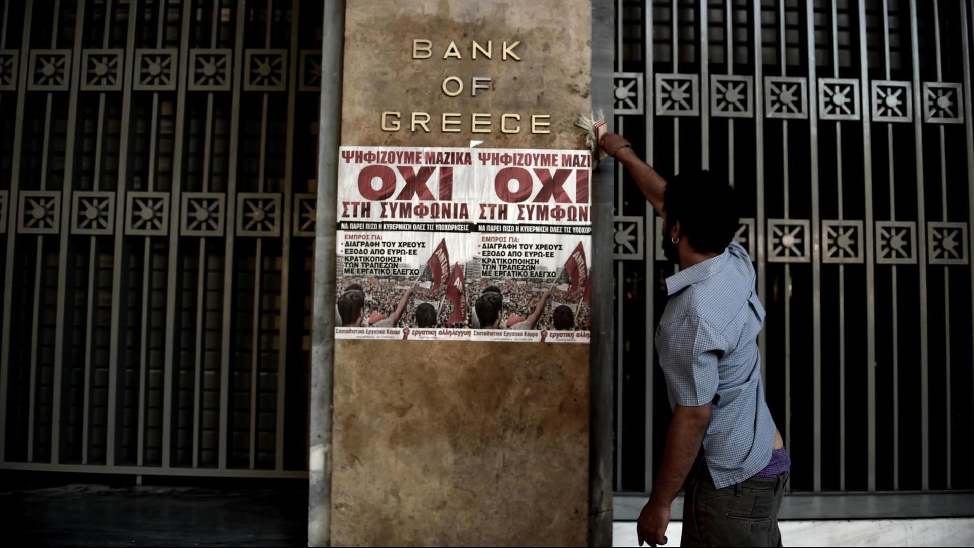 Ein Mann klebt an den Hauptsitz der griechischen Zentralbank ein Plakat, das für ein Nein beim Referendum am Sonntag wirbt.