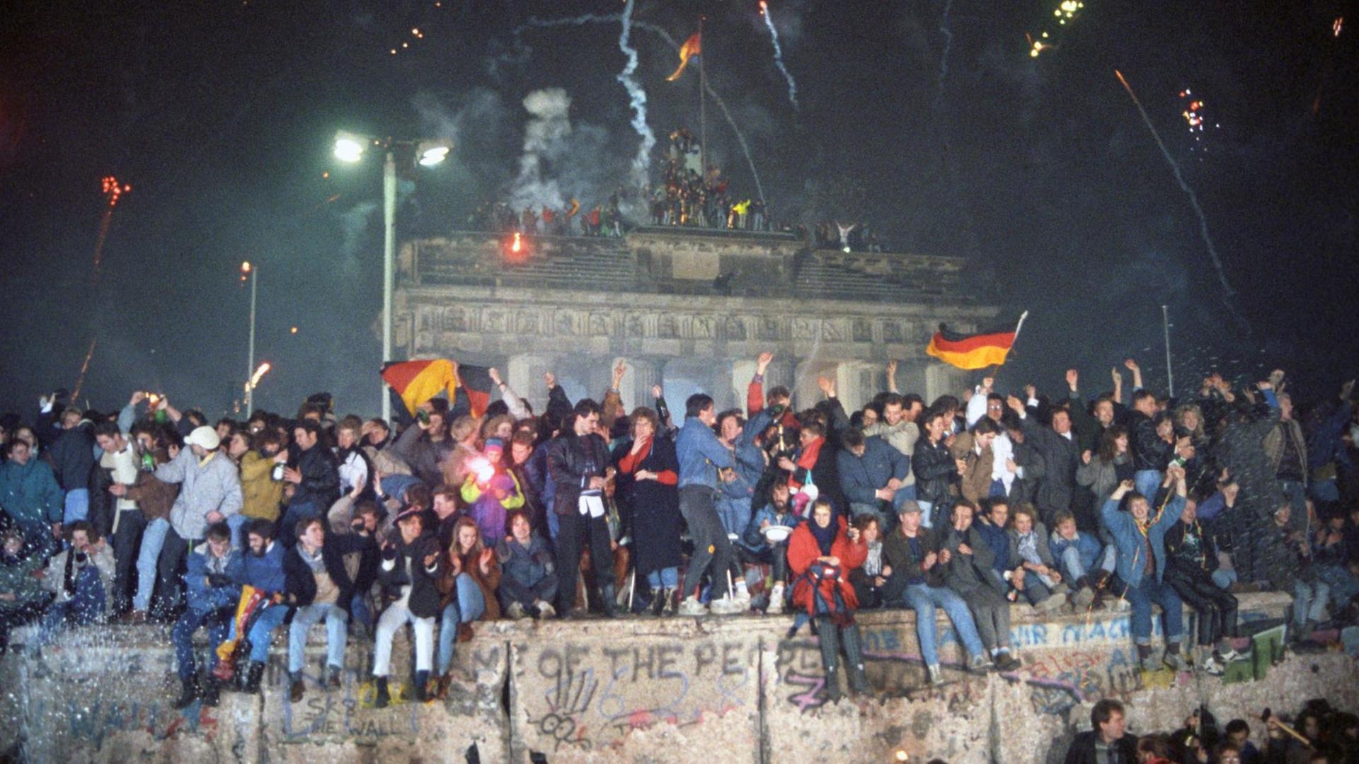 Mehrere hunderttausend Menschen aus Ost und West feiern am 31.12.1989 zum ersten Mal seit dem Bau der Berliner Mauer ausgelassen ein gesamtdeutsches Silvester am Brandenburger Tor.
