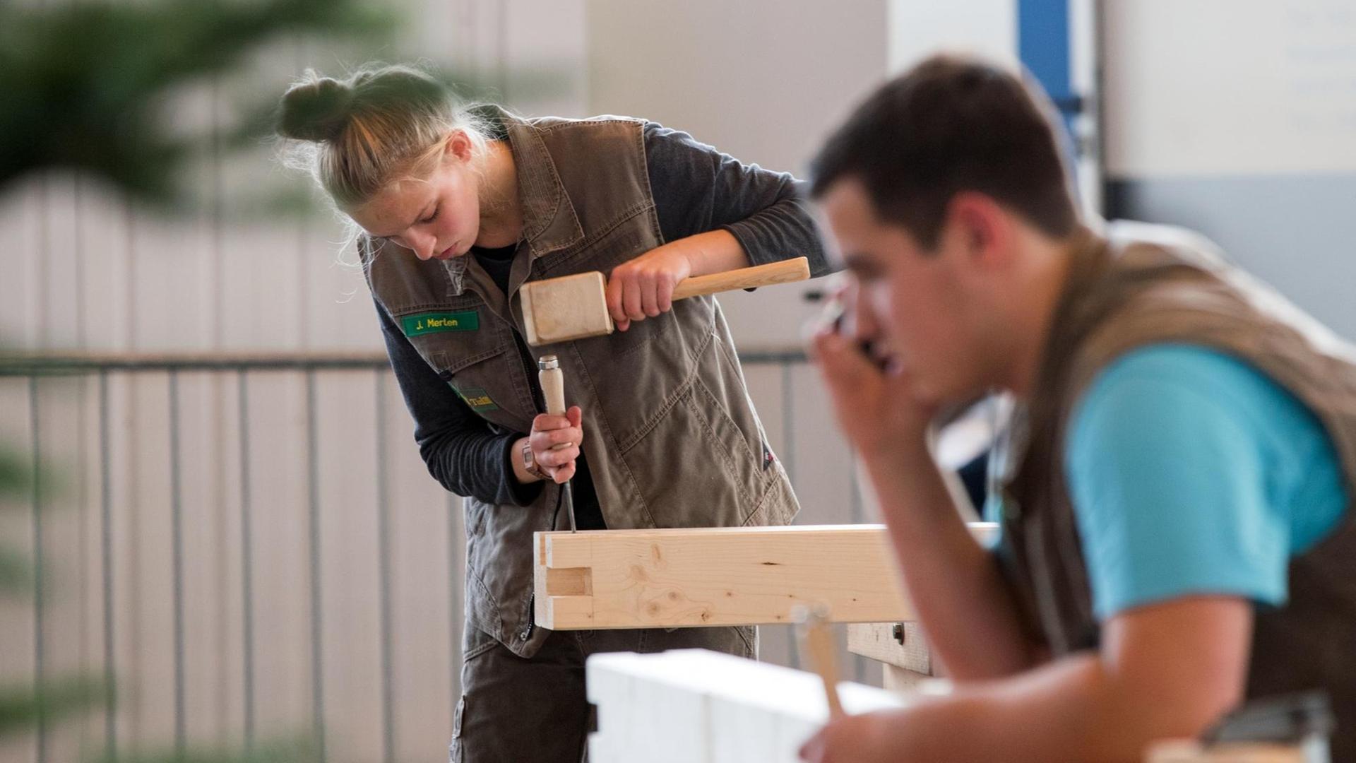 Eine Frau bearbeitet einen Holzbalken für ein Musterhaus, aufgenommen am 14.10.2016 auf der Landesbaumesse RoBau in Rostock.