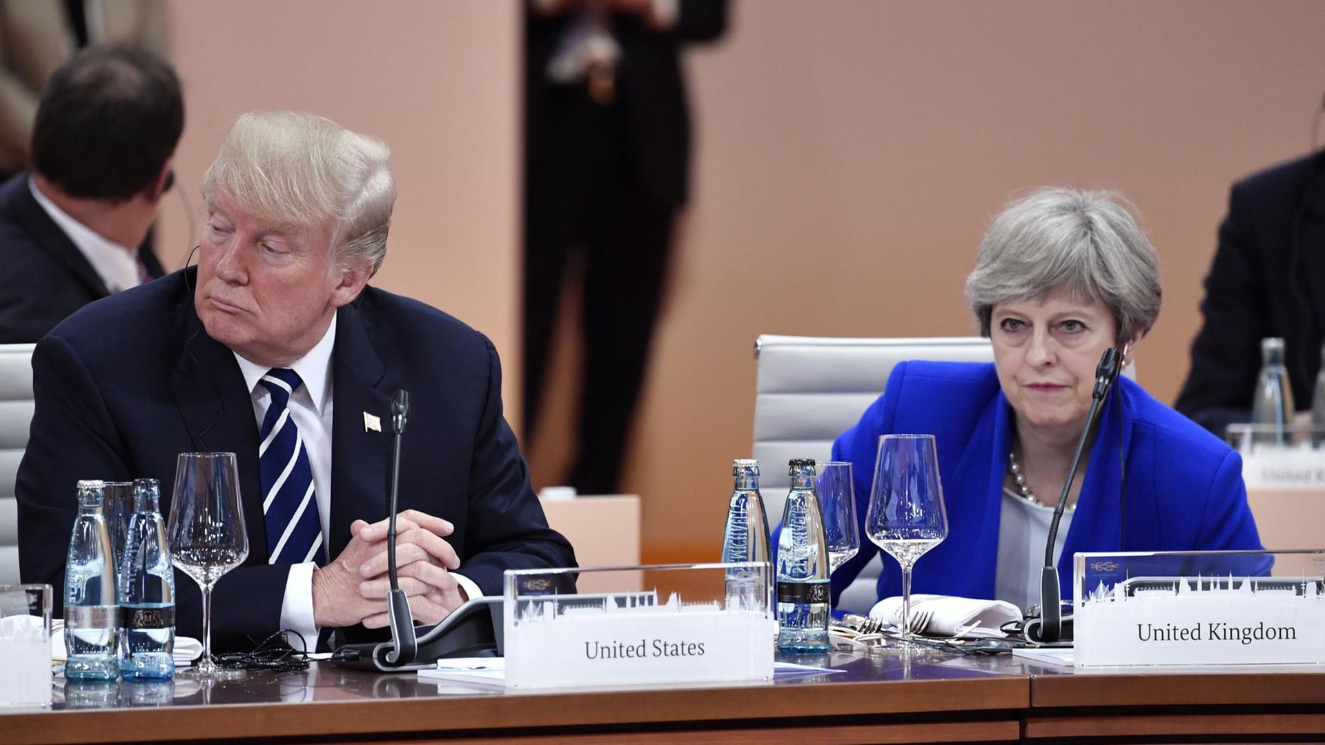 Der US-amerikanische Präsident Donald Trump und die britische Premierministerin Theresa May sitzen zu Beginn der ersten Arbeitssitzung beim G20-Gipfel am 07.07.2017 in Hamburg nebeneinander.