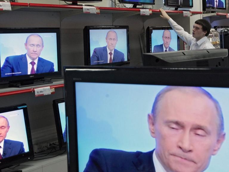 Wladimir Putin ist in einem Geschäft auf diversen TV-Bildschirmen zu sehen.
