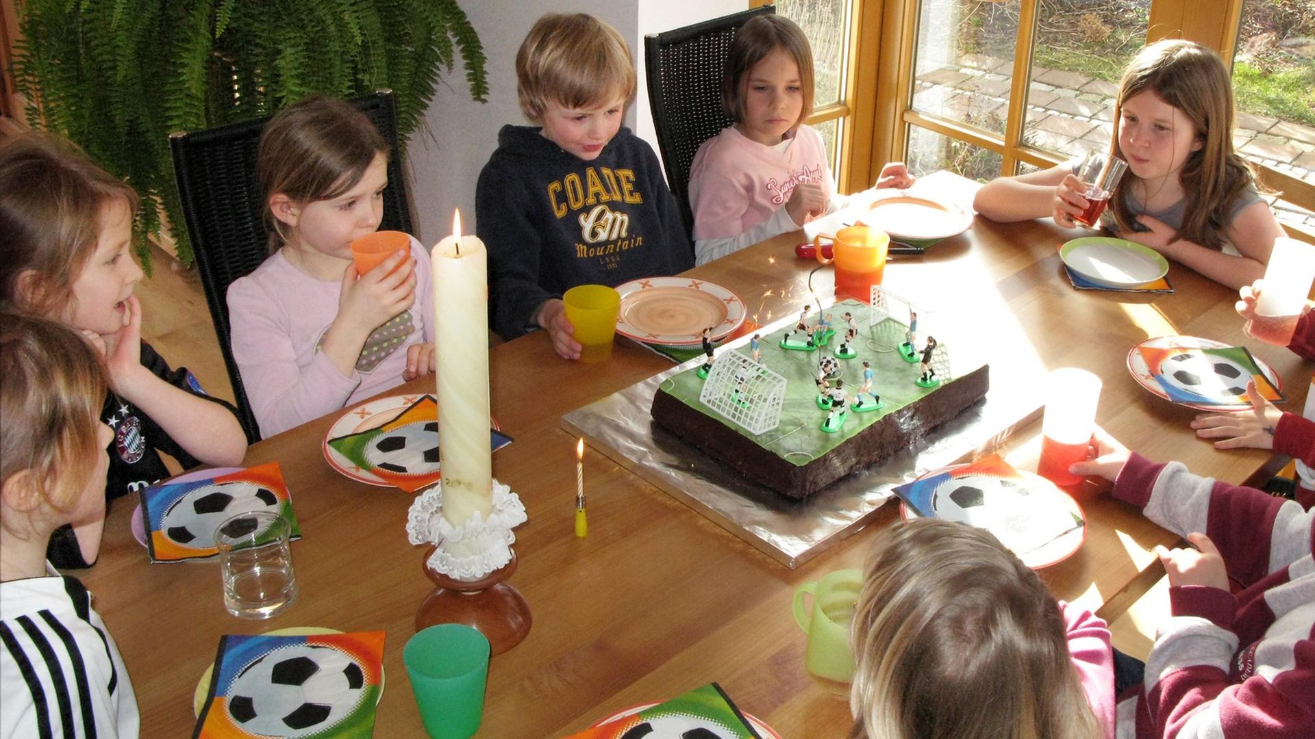 tellerKinder feiern einen Kindergeburtstag an einem bunt gedeckten Tisch.