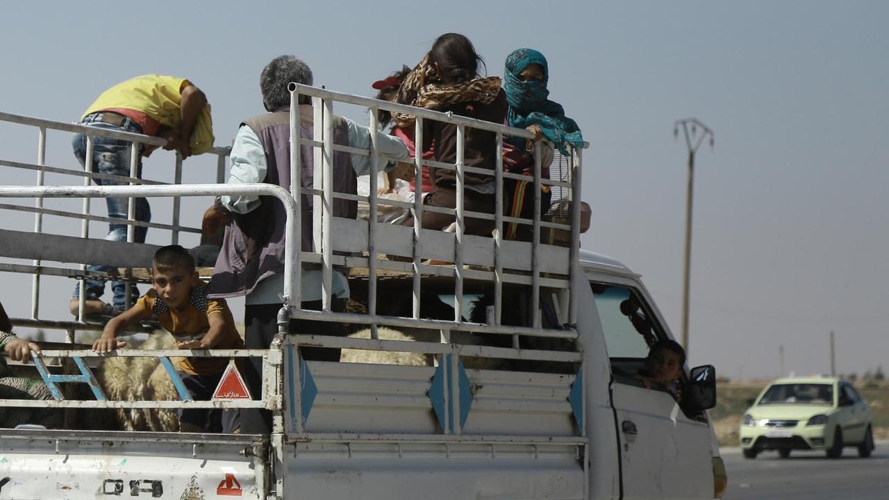 Sie sehen syrische Kurden, sie fliehen auf einem Lastwagen aus Hasaka im Nordosten des Landes.