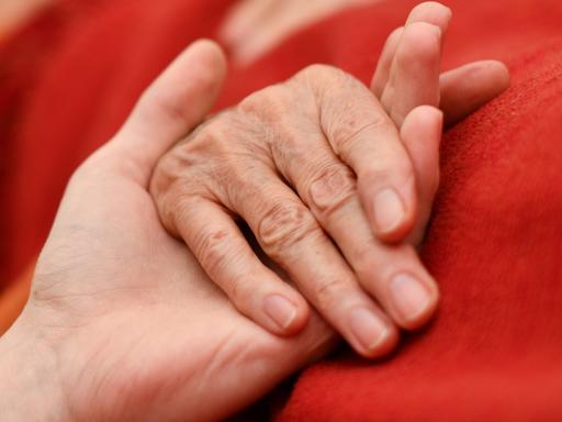 Die Hand eines alten Menschen wird von einer jüngeren Hand gehalten. 
