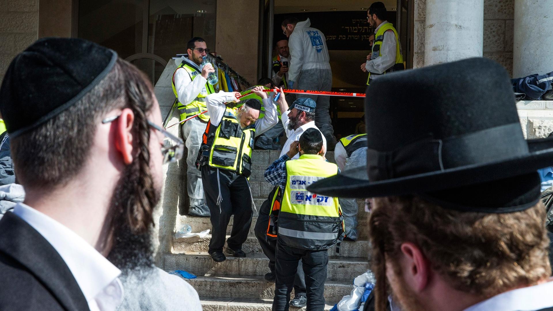Zwei ultra-orthodoxe Juden blicken auf die Synagoge, in der vier Menschen bei einem Anschlag starben.