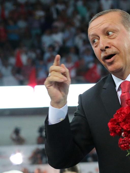 Recep Tayyip Erdogan wirft rote Blumen ins Publikum.