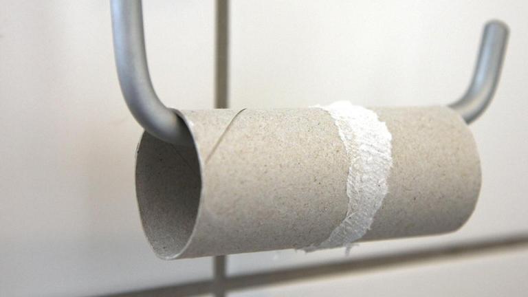 Aufgebrauchte Toilettenpapierrolle auf einem Halter in einem Badezimmer.