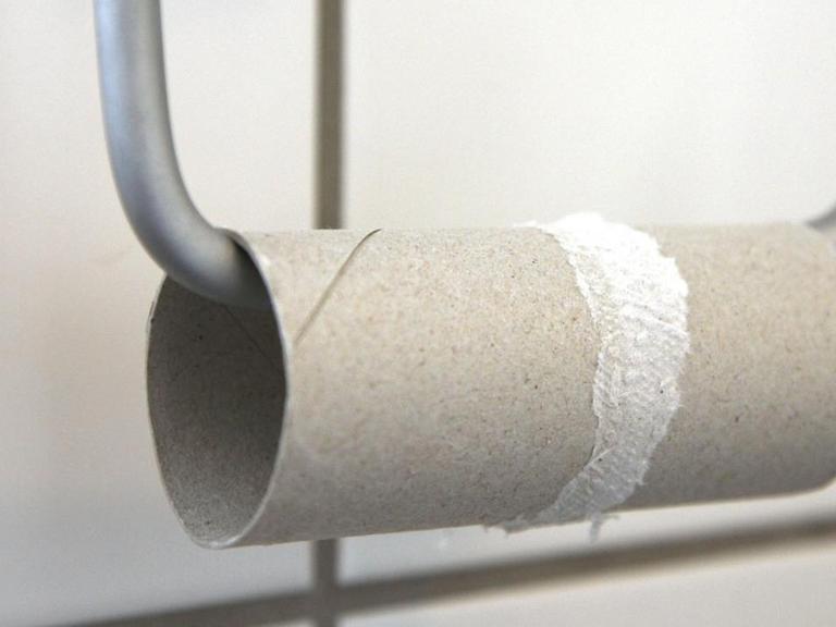 Aufgebrauchte Toilettenpapierrolle auf einem Halter in einem Badezimmer.