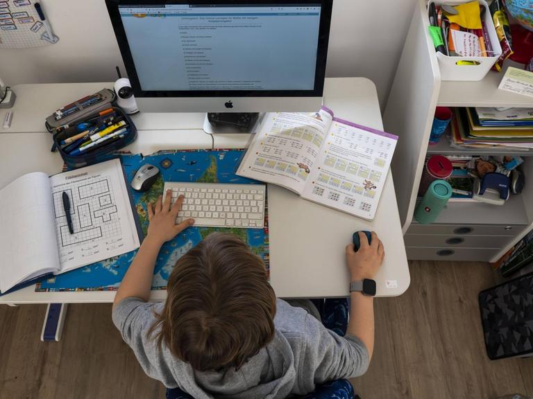 Ein Junge sitzt an seinem Schreibtisch vor dem Computer.