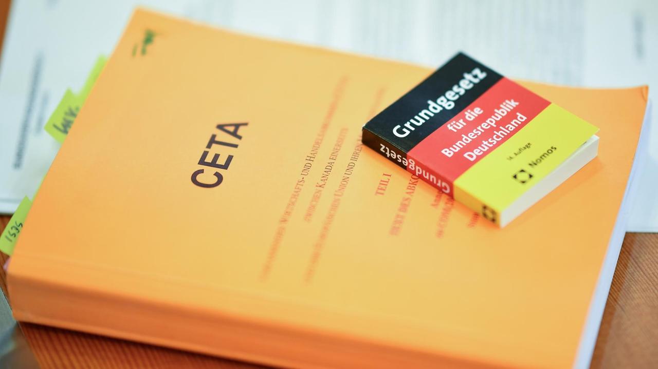 Zwei Bücher mit der Aufschrift "CETA" und "Grundgesetz" liegen in Karlsruhe vor Verhandlungsbeginn im Verhandlungssaal des Bundesverfassungsgerichts.