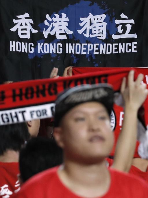 Einige Fans der Fußballnationalmannschaft von Hongkong halten einen Banner mit der Aufschrift "Hong Kong Unabhängigkeit" hoch.
