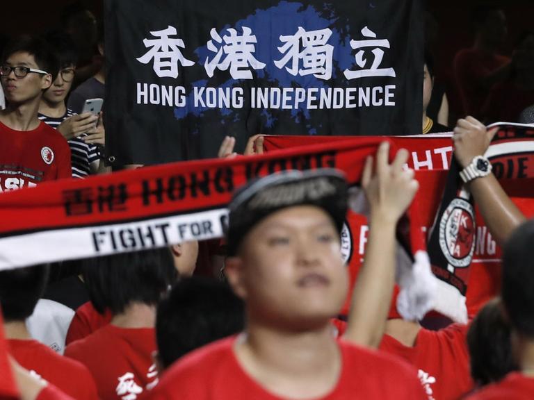 Einige Fans der Fußballnationalmannschaft von Hongkong halten einen Banner mit der Aufschrift "Hong Kong Unabhängigkeit" hoch.