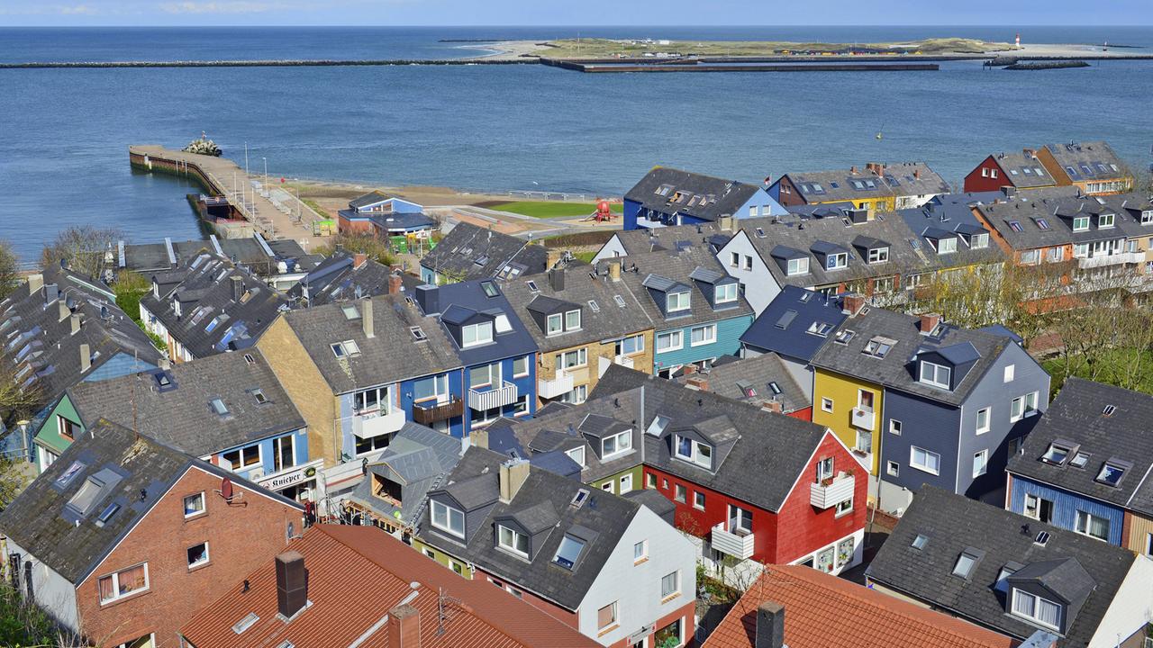 Viele bunte Häuser auf dem Unterland von Helgoland mit grauen Dächern und der Nordsee am Horizont