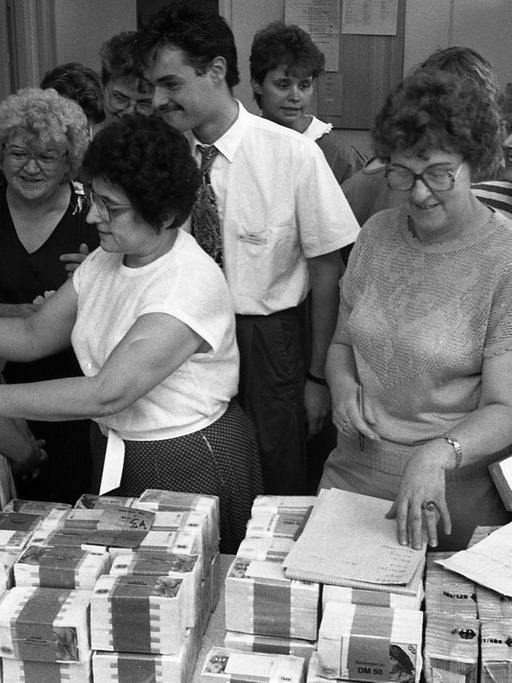 Mitarbeiter einer Sparkasse in Leipzig zahlen am 1. Juli 1990 Geld aus und tauschen die Konten der DDR-Bürger.