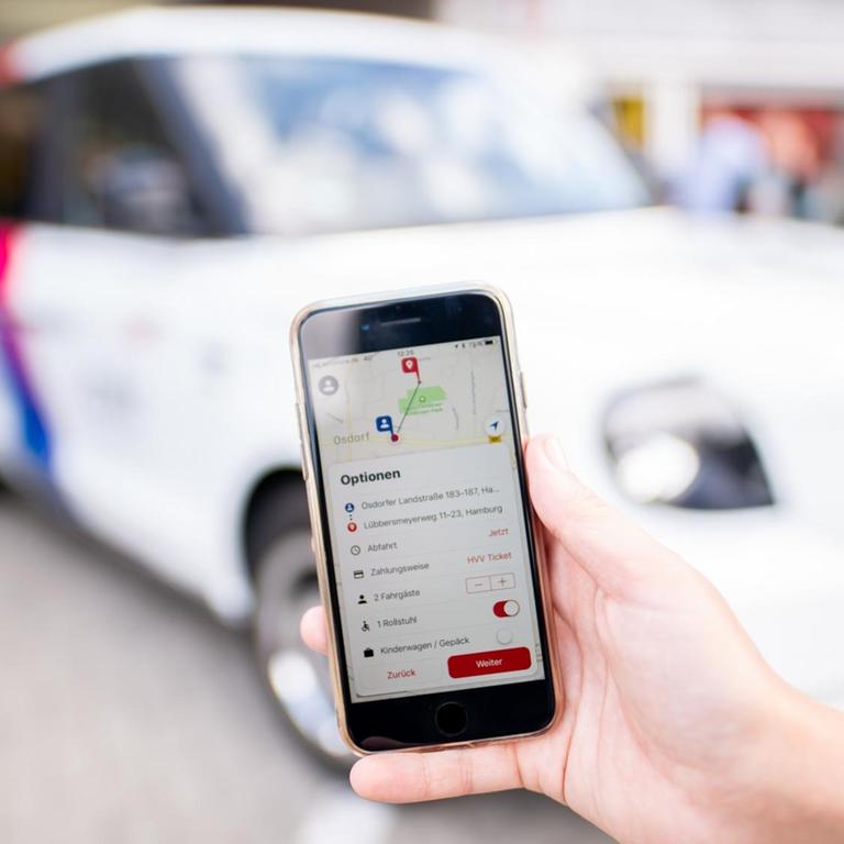Smartphone mit Ridesharing-App vor E-Auto