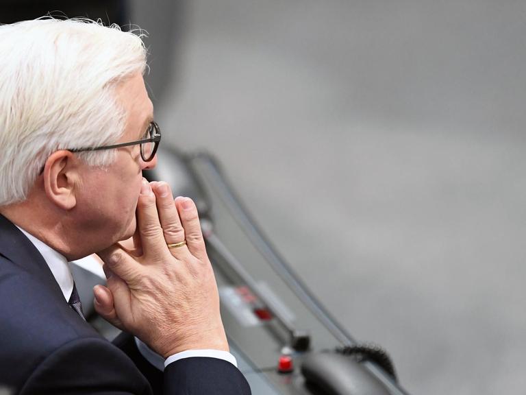 Der Bundespräsident Frank-Walter Steinmeier sitzt im Bundestag mit ineinander verschlungene Händen vor dem Gesicht.
