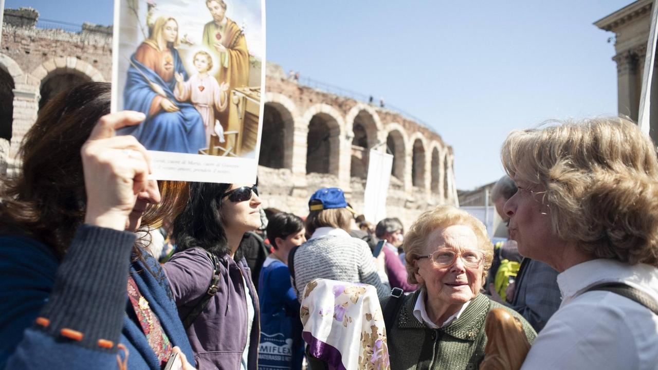Versammlungsteilnehmer vor einem historischen Gebäude in Verona, Plakat mit Joseph, Maria und dem Jesuskind im Vordergrund