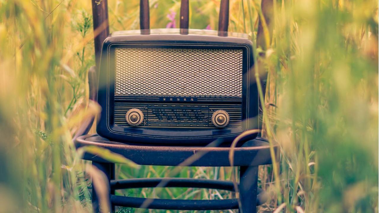 Ein altes Transistorradio steht auf einem Stuhl in der Mitte eines Feldes