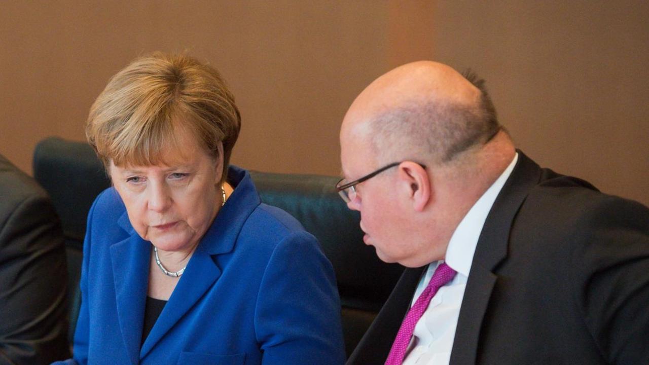 Bundeskanzlerin Angela Merkel (CDU) und Peter Altmaier (CDU), Chef des Bundeskanzleramtes, unterhalten sich am 07.10.2015 zu Beginn der Sitzung des Bundeskabinetts im Bundeskanzleramt in Berlin, links daneben sitzt Bundeswirtschaftsminister Sigmar Gabriel (SPD).