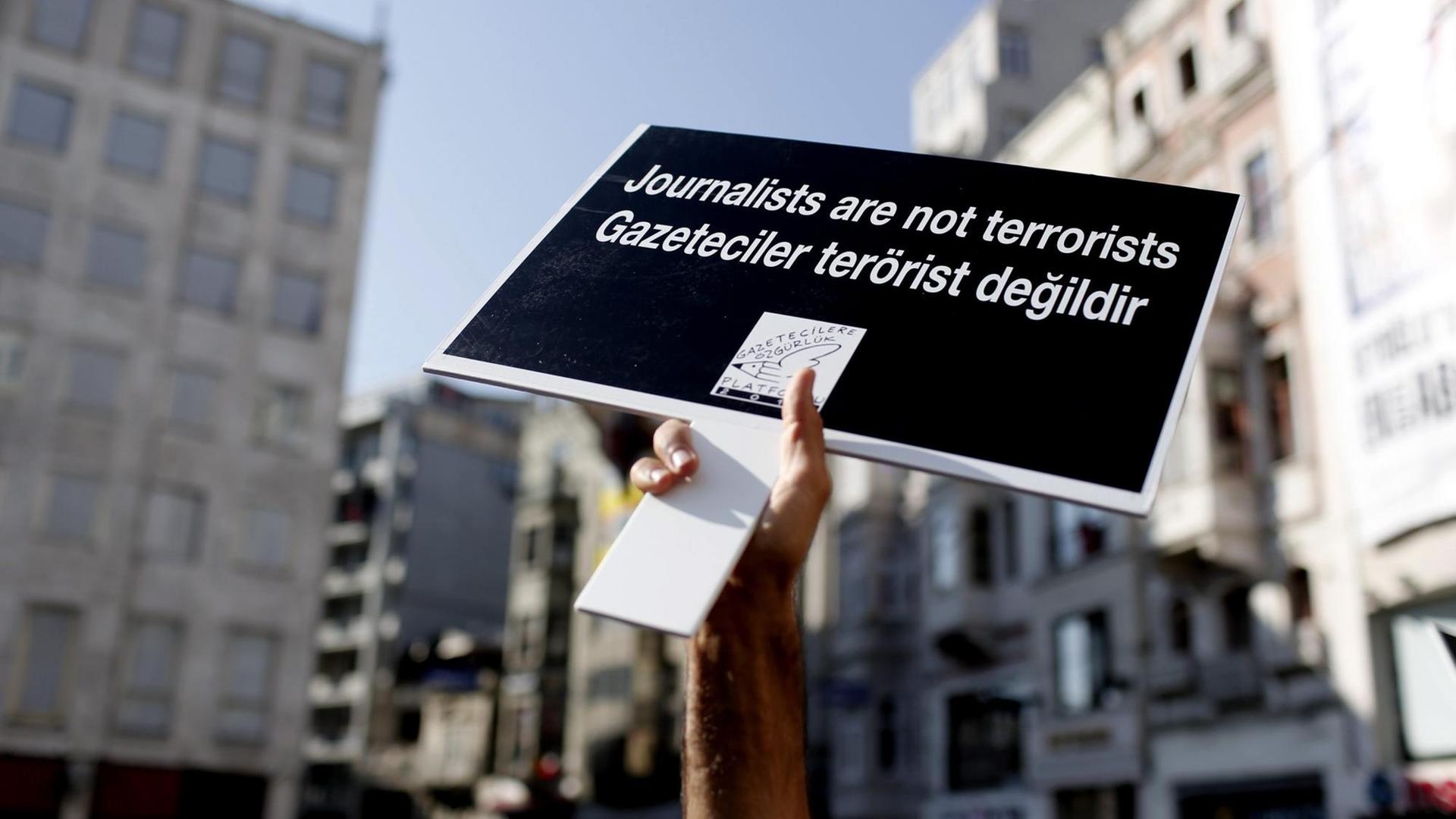 Ein Demonstrant reckt ein Plakat mit der Aufschrift "Journalisten sind keine Terroristen" in die Höhe.