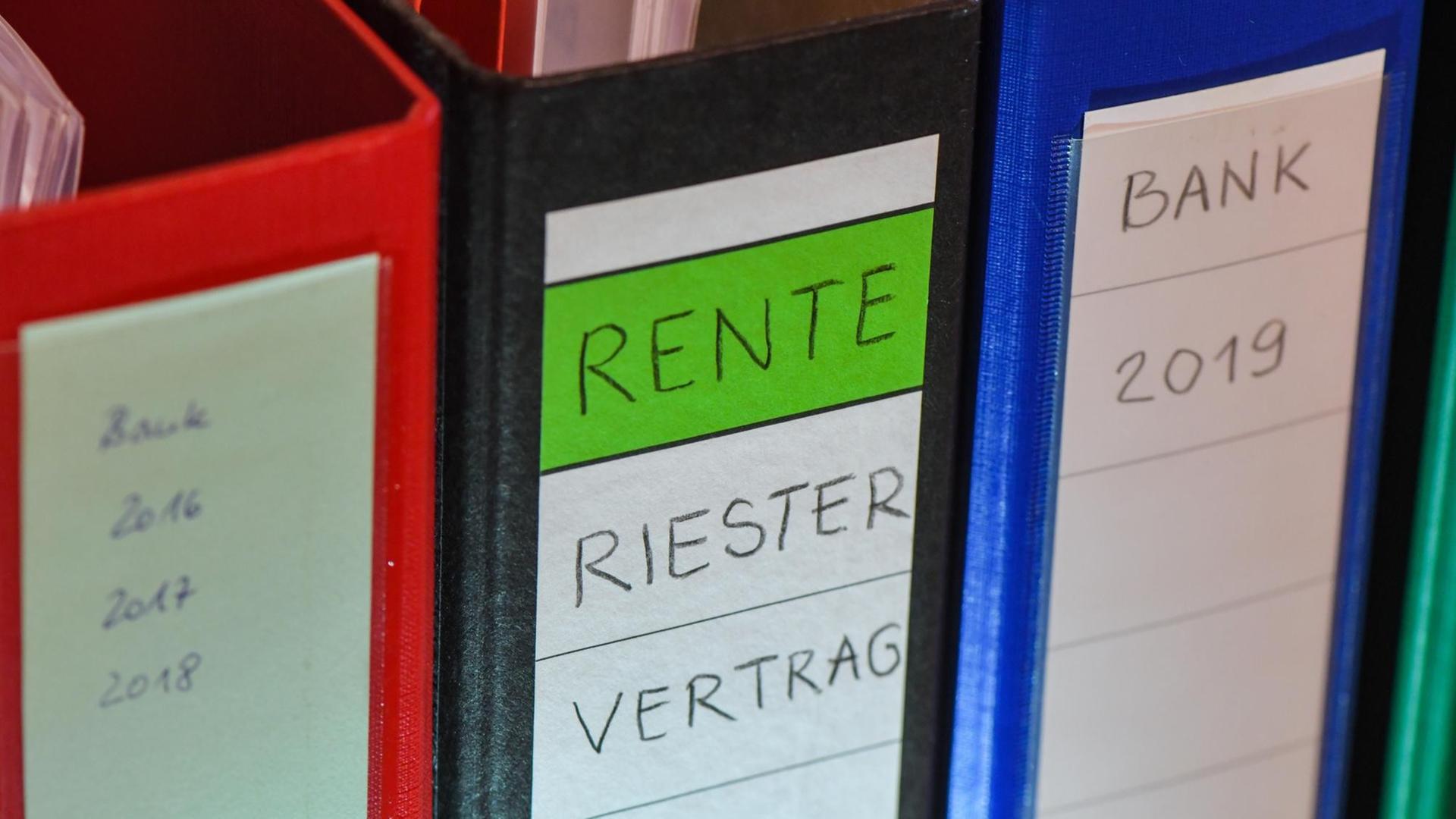 Ein Ordner mit der Aufschrift "Rente Riester Vertrag" steht zwischen anderen Aktenordnern.