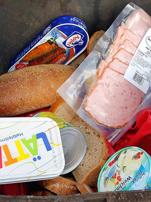 Ein Mülltonne ist bis zum Rand mit teilweise noch verpackten Lebensmitteln gefüllt. Jeder Bundesbürger wirft im Schnitt 82 Kilogramm Lebensmittel im Jahr weg.Oftmals ist der Ablauf des Mindesthaltbarkeitsdatums der Grund.