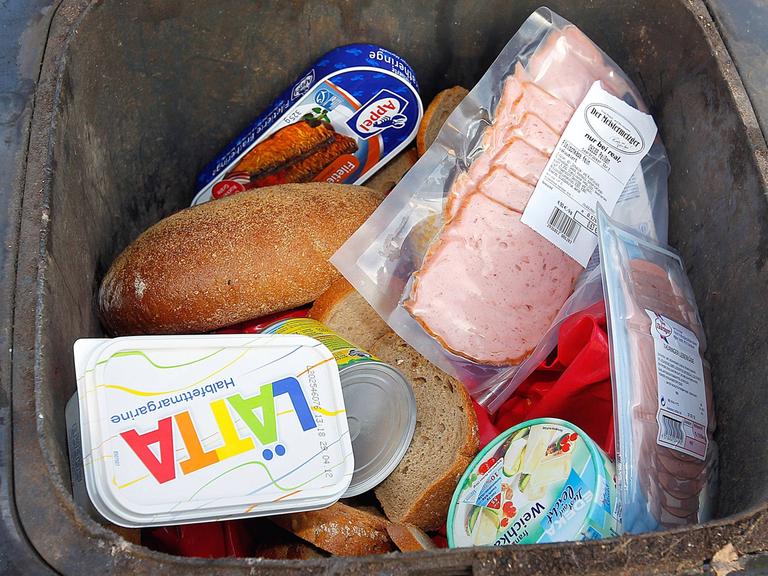 Ein Mülltonne ist bis zum Rand mit teilweise noch verpackten Lebensmitteln gefüllt. Jeder Bundesbürger wirft im Schnitt 82 Kilogramm Lebensmittel im Jahr weg.Oftmals ist der Ablauf des Mindesthaltbarkeitsdatums der Grund.