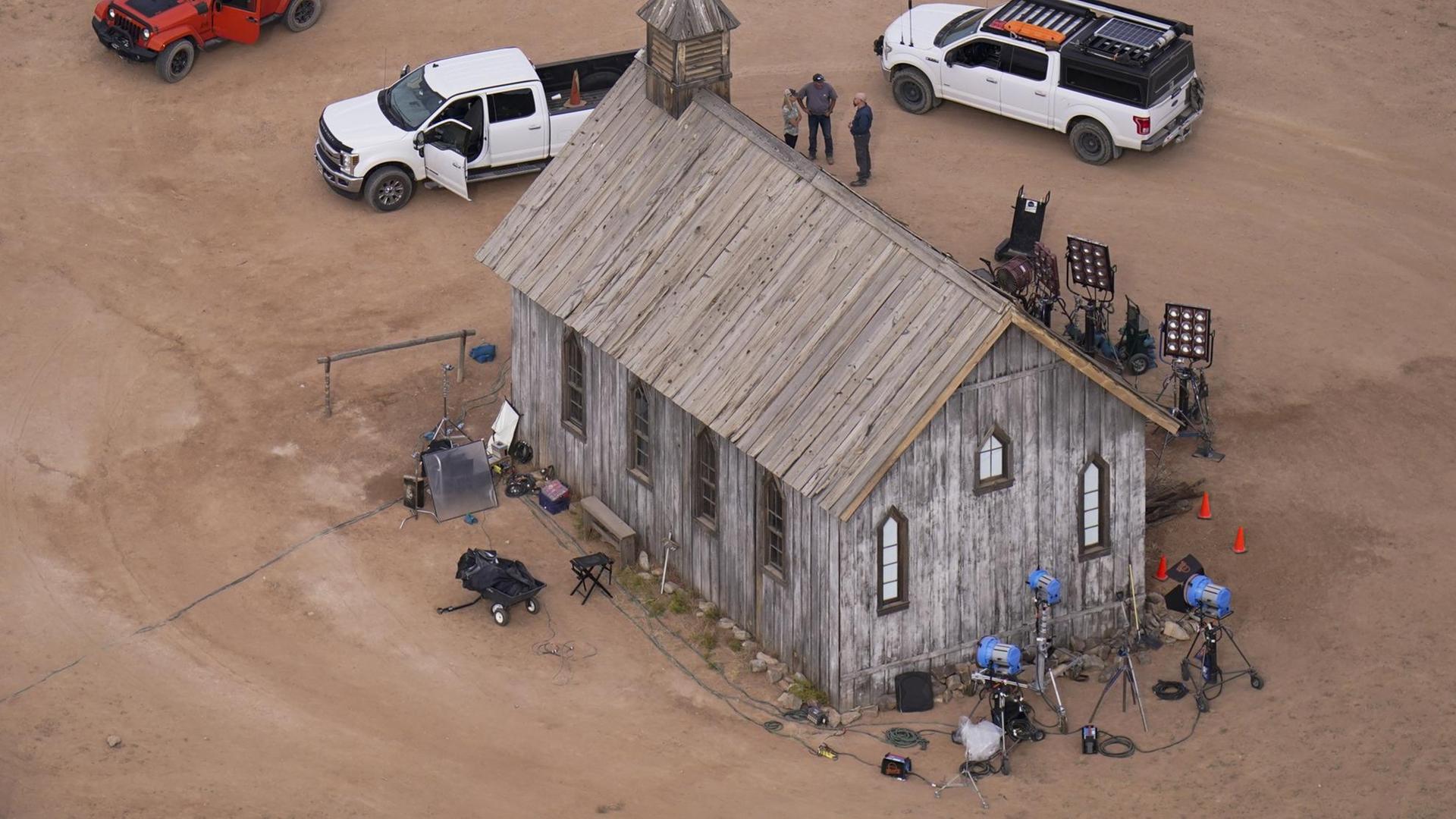 Das aus der Luft aufgenommene Foto zeigt eine aus Holz gebaute Kirche. Davor Menschen, Filmkameras auf Stativen, sowie ein rotes und zwei weiße Fahrzeuge.