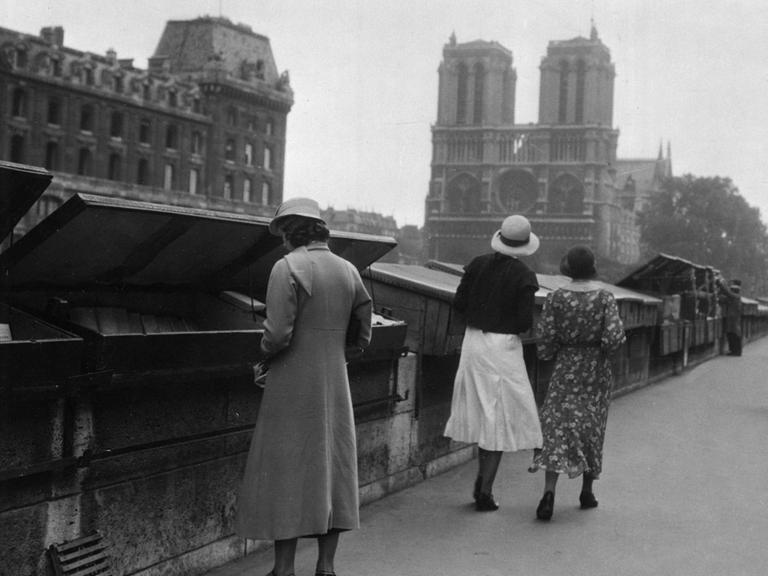 Passanten an Buchständen an der Seine am Anfang des 20. Jahrhunderts, im Hintergrund Notre-Dame.