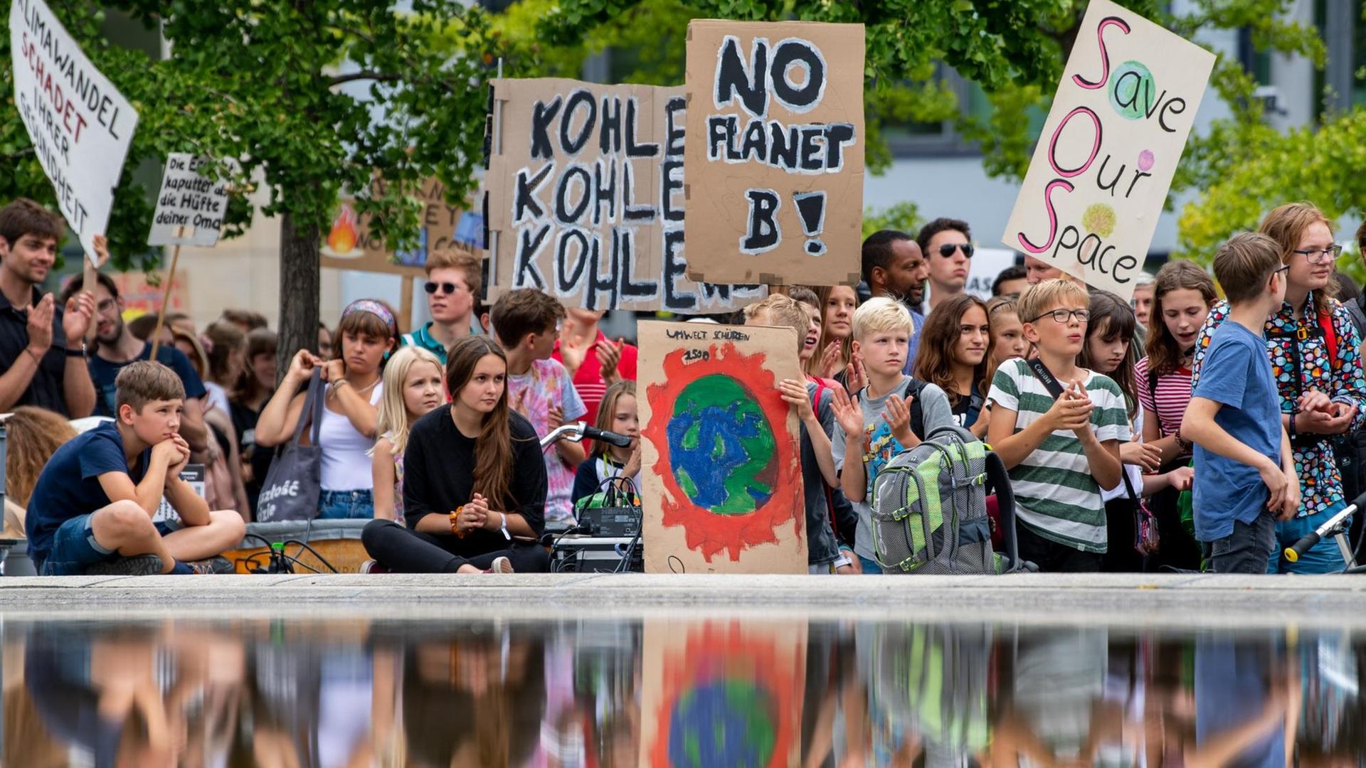 Teilnehmer der Klimademonstration "Fridays for Future" stehen mit ihren Transparenten im Invalidenpark.