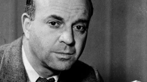 Ein Schwarzweiß Foto zeigt den Schriftsteller John Dos Passos in den späten 1930er-Jahren in die Kamera blickend