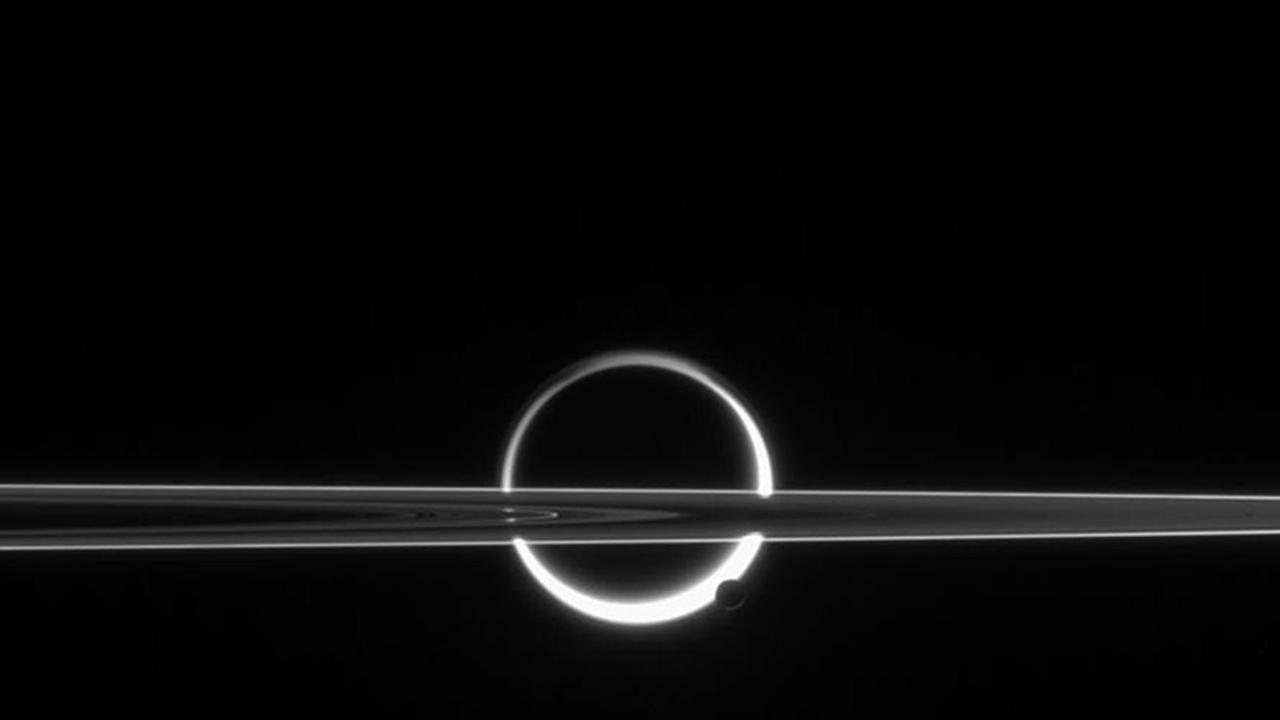 Die zum Kreis geschlossene Titansichel hinter den Saturnringen und mit einem kleineren Mond im Vordergrund