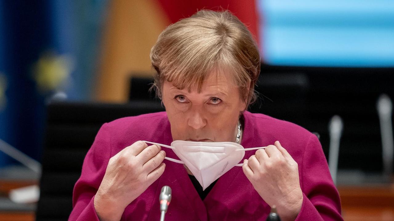 Bundeskanzlerin Angela Merkel nimmt zu Beginn der Sitzung des Bundeskabinetts im Kanzleramt ihre Maske ab