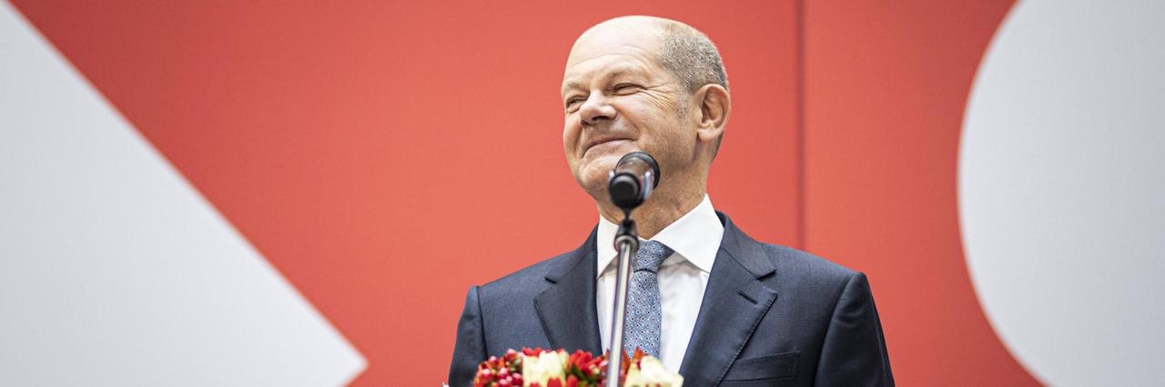Der Kanzler-Kandidat von der SPD, Olaf Scholz hält einen Blumen-Strauß in der Hand und lächelt.