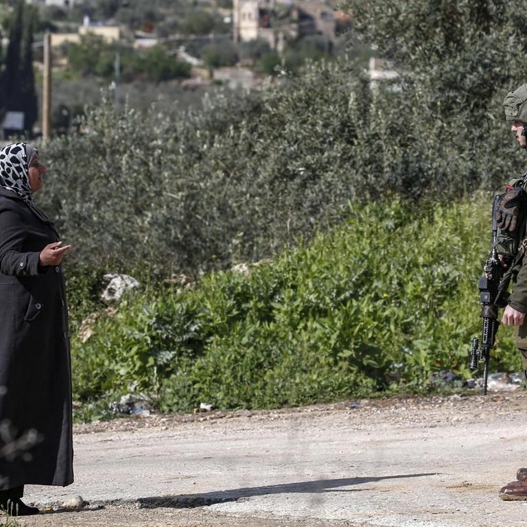 In der Nähe der jüdischen Siedlung Ariel im Westjordanland spricht eine Palästinenserin mit einem israelischen Soldaten  