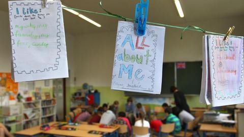 Von Schülerinnen und Schülern auf englisch gestaltete persönliche Heftchen hängen während des Unterrichtes in einem Klassenzimmer an einer Leine