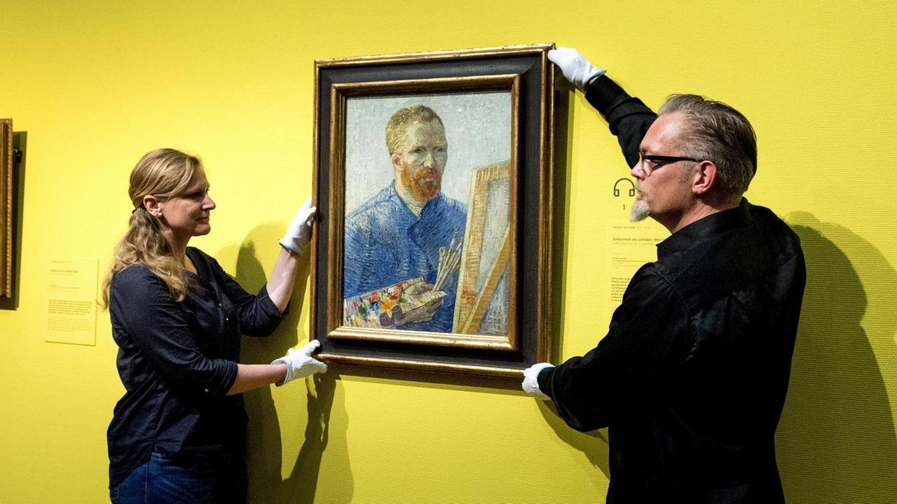 Zwei Mitarbeiter hängen van Goghs "Selbstbildnis vor der Staffelei" auf nachdem das Museum in Amsterdam umgebaut wurde.