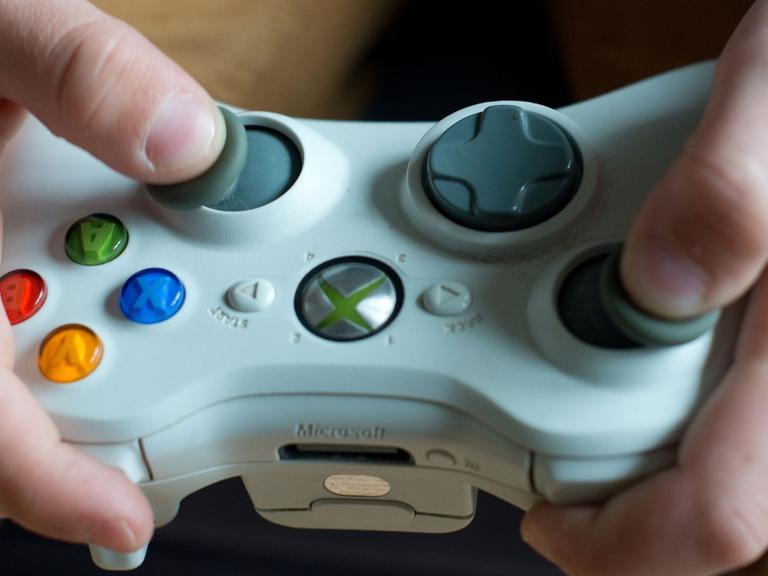 Eine Spielekonsole wird von zwei Händen gehalten. 