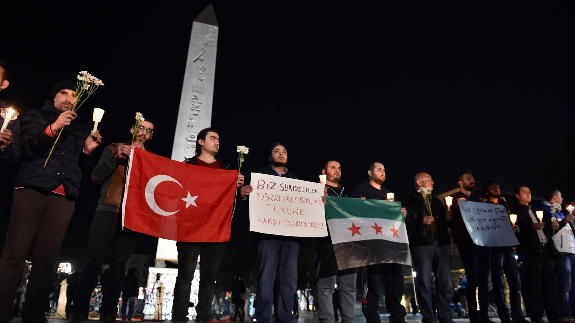 Vor einem Obelisken in Sultanahmet stehen am Abend Syrer mit ihrer Flagge und der der Türkei.