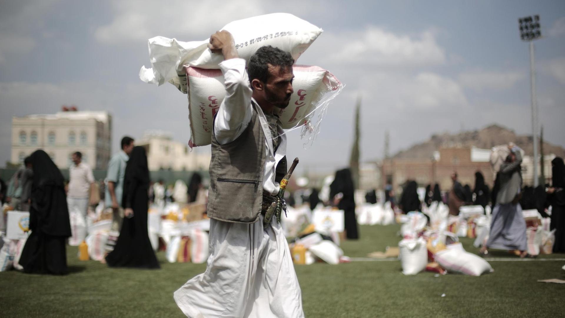 Ein Mann trägt im Jemen Säcke mit Getreide.