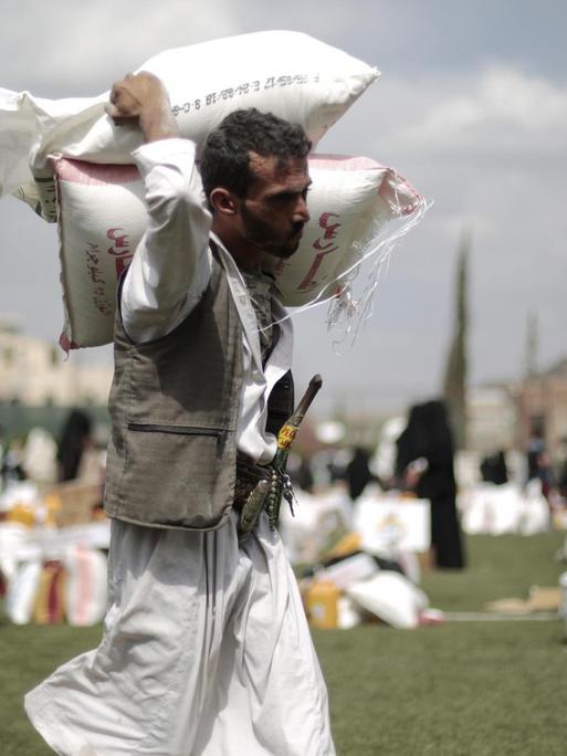 Ein Mann trägt in Sanaa (Jemen) Säcke mit Getreide.