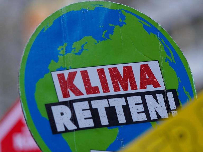 Ein Plakat auf einer Klima-Demo zeigt eine Weltkugel, auf der "Klima retten" steht"