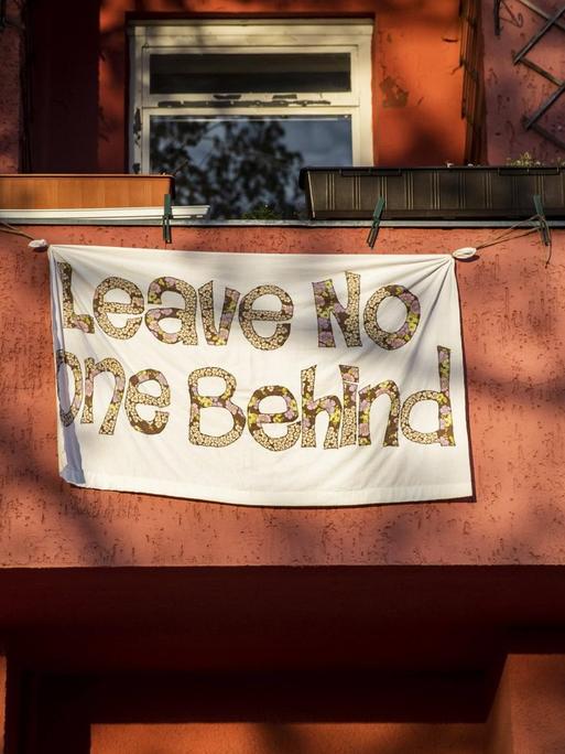 Ein Banner mit dem Schriftzug "Leave Noone Behind" hängt am 17. April 2020 in Berlin an einem Balkon.